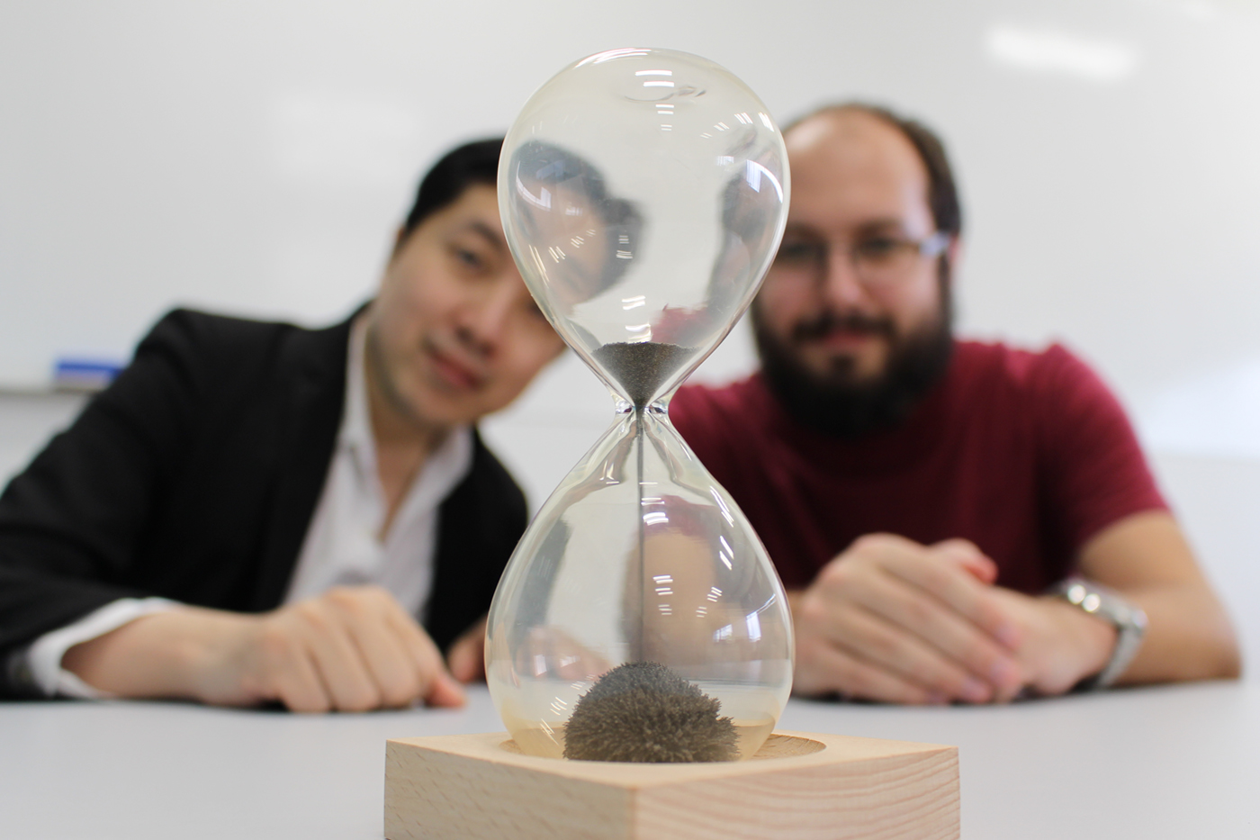 Researchers Mile Gu and Thomas Elliott pictured with an hourglass