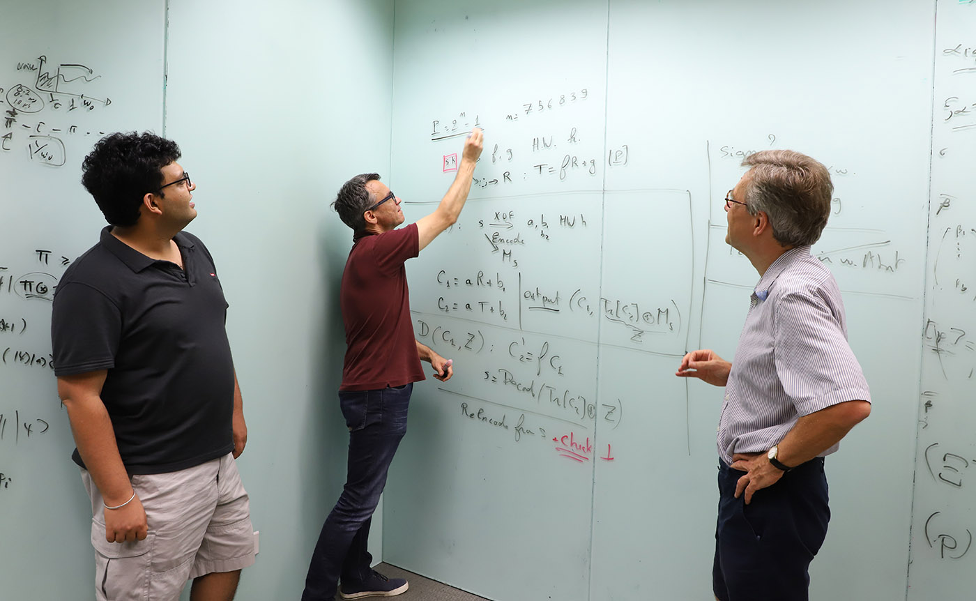 Three researchers at the Centre for Quantum Technologies pictured at a whiteboard with equations