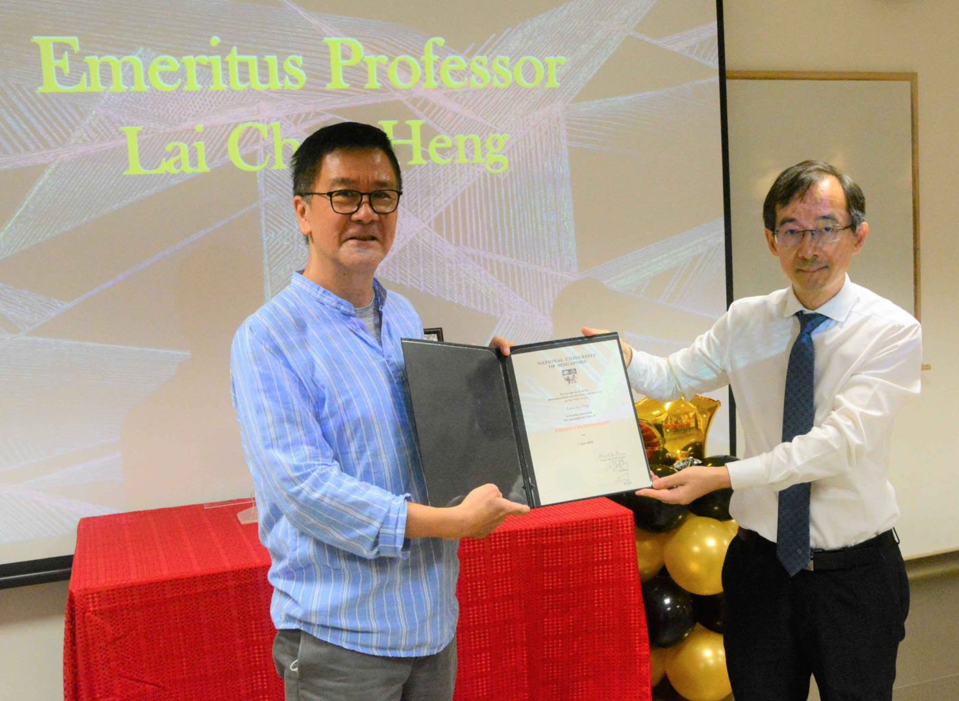 NUS physicists Lai Choy Heng and Gong Jiangbin stand holding a certificate between them. 